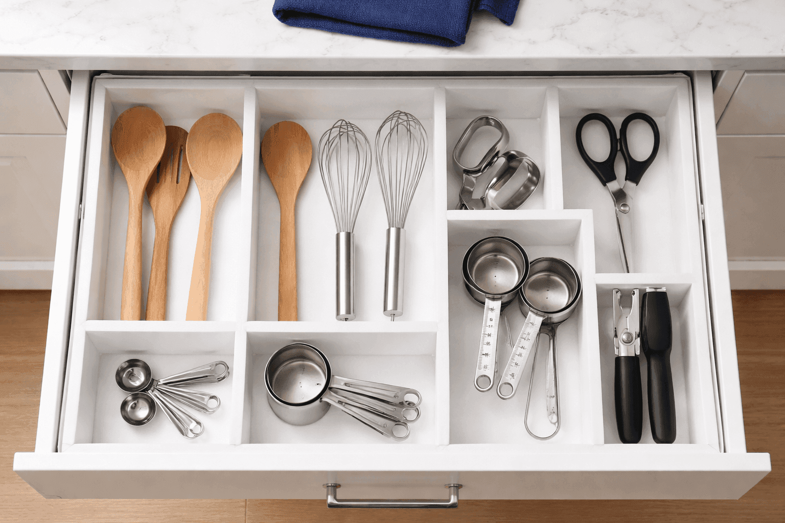 Custom foam board drawer organizer with grid pattern dividing kitchen utensils into neat compartments inside white drawer