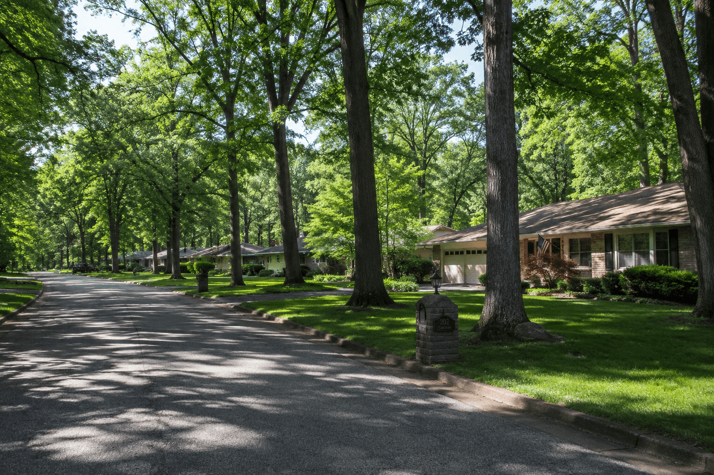A wooded residential street in Valparaiso, Indiana, with mature trees and mid-century ranch homes set back on generous lots in a quiet neighborhood.