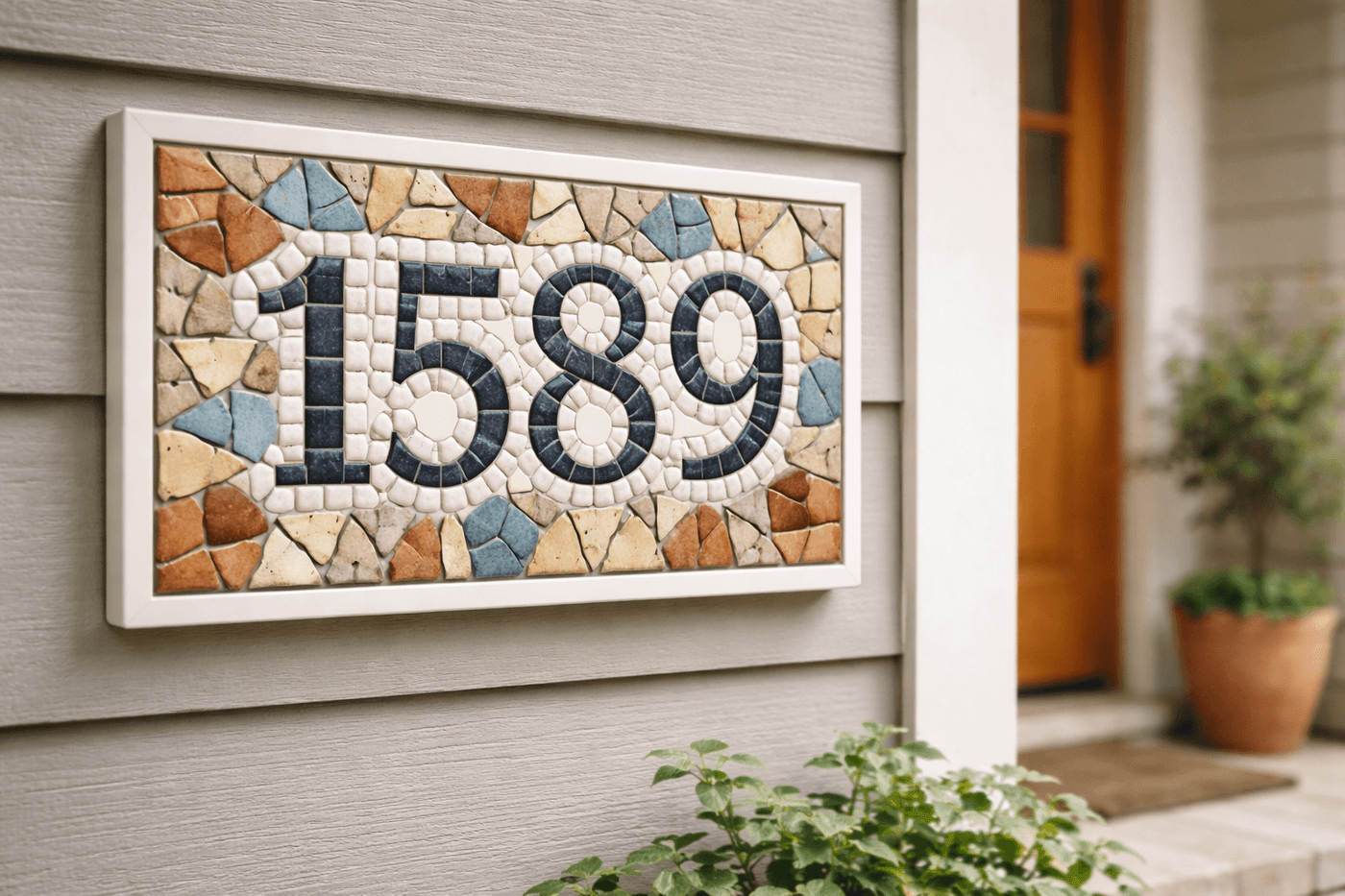 Handmade mosaic address sign with colorful ceramic tile pieces arranged around bold house numbers mounted on a wood backing beside a front door